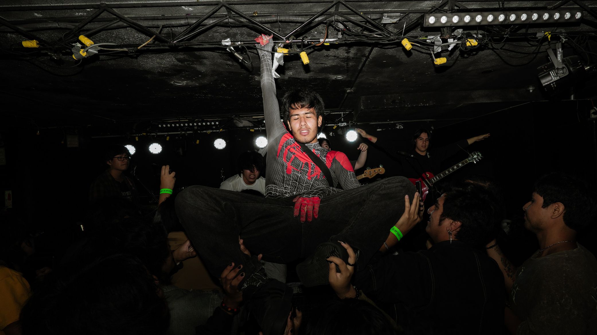 Un asistente hace crowdsurfing sobre el público durante un show de Ok Boomer, iluminado con flash.